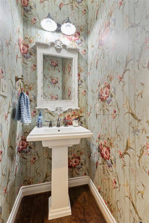 This is a charming powder room featuring a classic pedestal sink. It has a decorative mirror and dual light fixtures. Darling half bath.