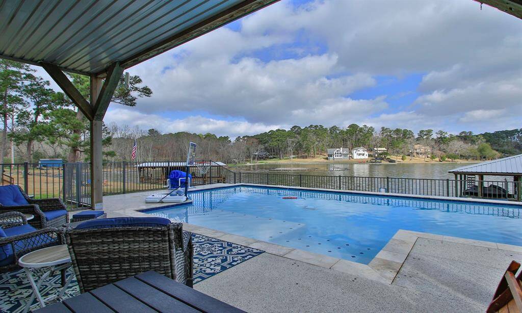 This serene lakeside property features a covered patio overlooking a private pool and scenic water views, perfect for relaxation and entertaining.