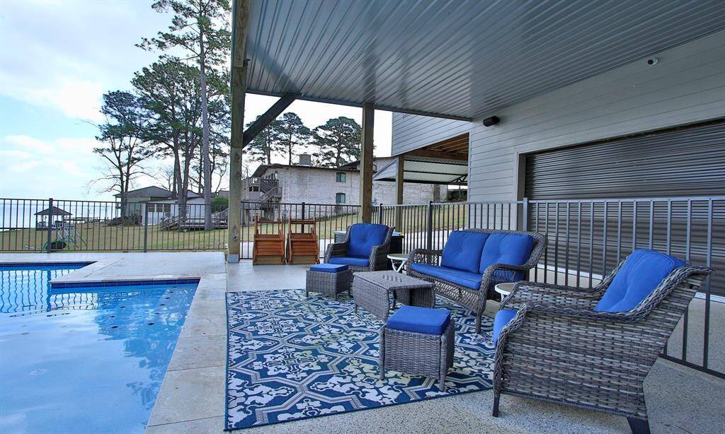 This photo showcases a serene backyard with a pool overlooking a scenic lake. Great covered patio to get out of the sun if wanted! The area is surrounded by trees and a few neighboring houses, offering a peaceful and picturesque setting perfect for outdoor activities.