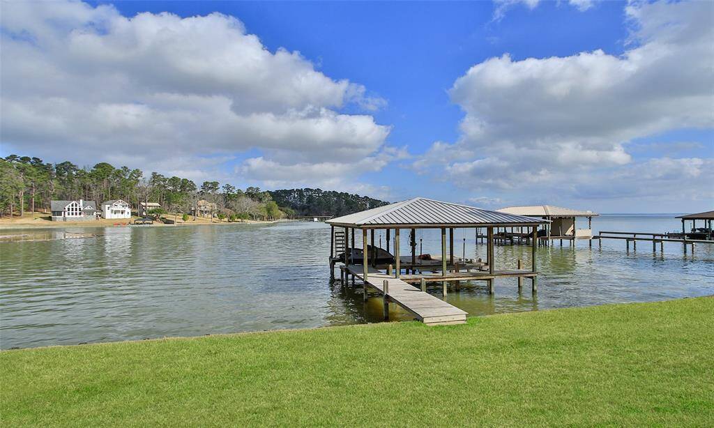 This photo showcases a serene lakeside setting with a covered boat dock and wooden walkway. It offers direct water access and picturesque views, perfect for a waterfront lifestyle.
