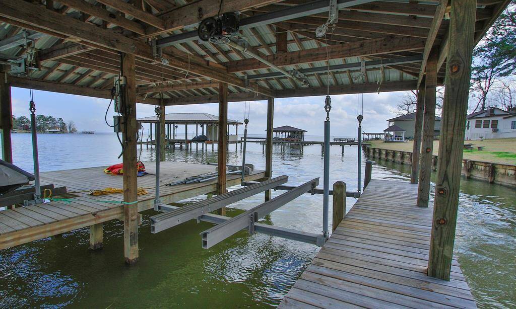 This photo showcases a waterfront property with a private boat dock equipped with a covered lift. The dock offers direct access to the water. Great place to go fishing!