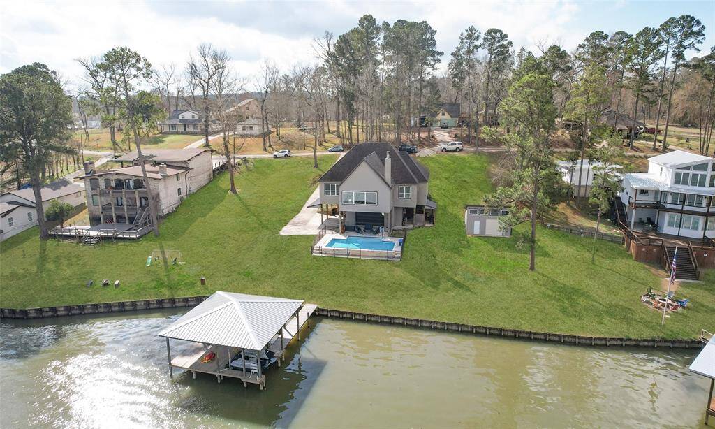 This waterfront home features a spacious backyard with a large lawn leading to a private dock. It includes a swimming pool and offers scenic views, perfect for those seeking a serene and picturesque setting.