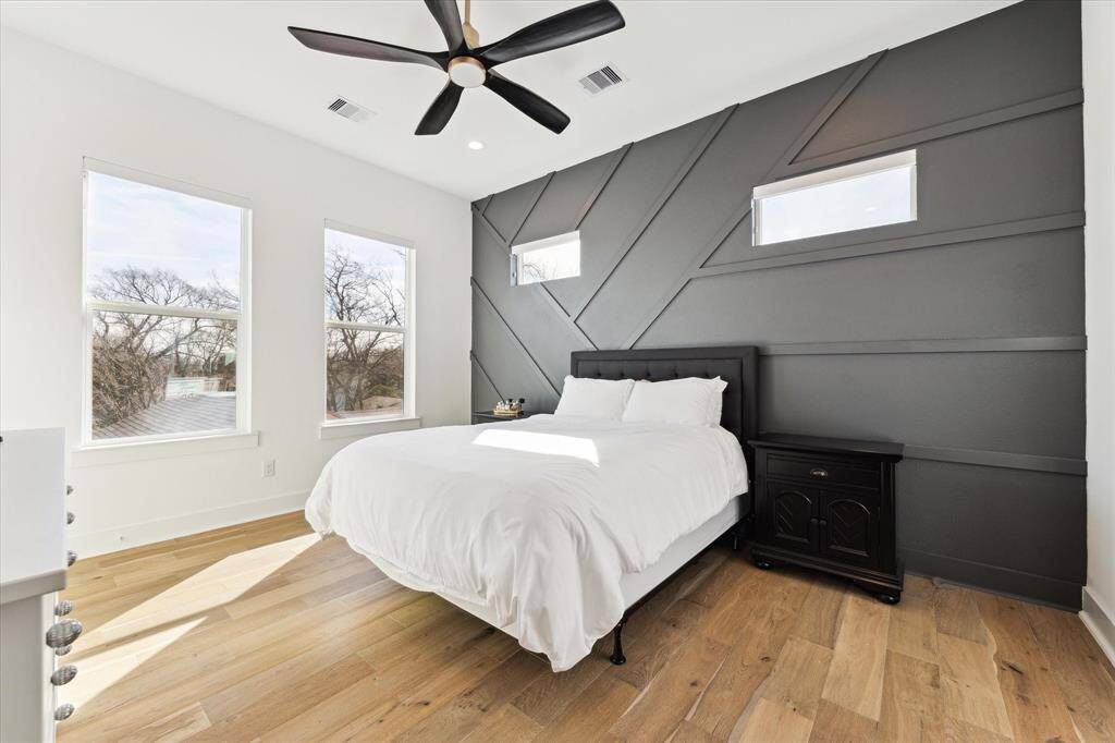 Lovely primary bedroom with accent wall and thoughtfully placed transom windows that provide additional light without losing the functionality of the wall.