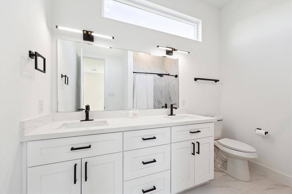Second full bath has dual sinks, tub / shower, transom window for natural light, and plenty of storage.