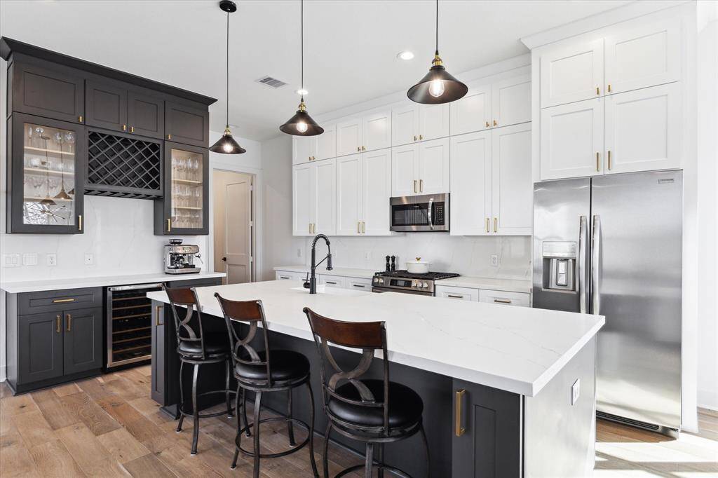 Gorgeous kitchen! Quartz countertop with farm sink, pendant lighting over the island, beautiful bar area with beverage refrigerator, stainless appliances, oven with gas cooktop: This is a kitchen you'll be thrilled to entertain in!