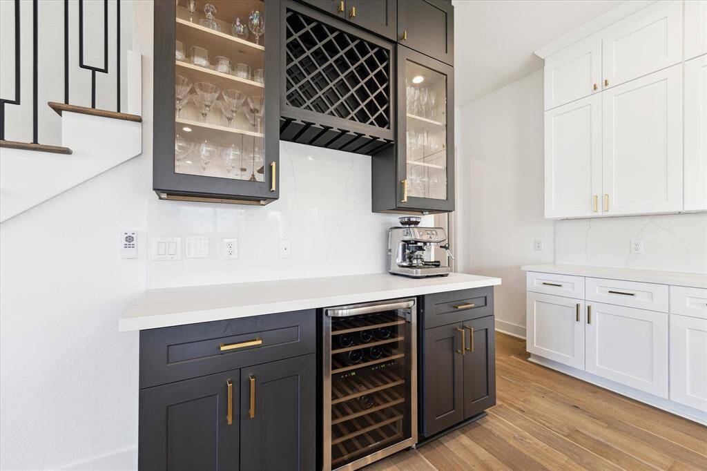 The bar area adds a lovely accent to the kitchen, with dark cabinetry, glass fronts on two display cabinets, beverage refrigerator, wine storage, and storage!