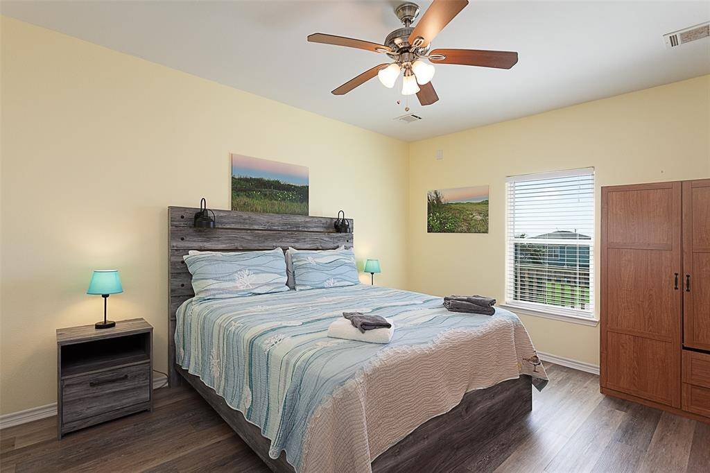 Primary bedroom has a king sized bed, ceiling fan & plenty of storage.
