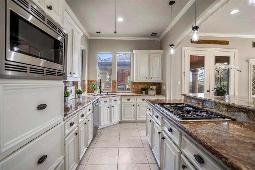 The large kitchen features an abundance of granite countertop space with gas cooktop, corner sinks, and pendant lighting, Sub Zero, Thermador and Kitchenaid appliances. Painted cabinets with updated hardware and faux technique. Bar top seating great for food display for parties