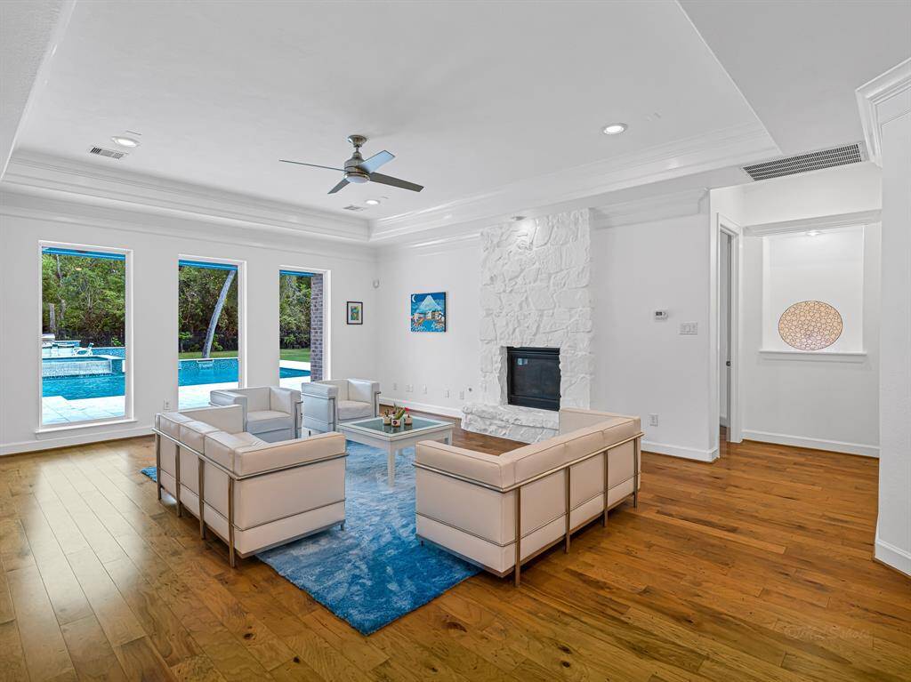 Massive family room with beautiful pool views and a fireplace with a stone surround