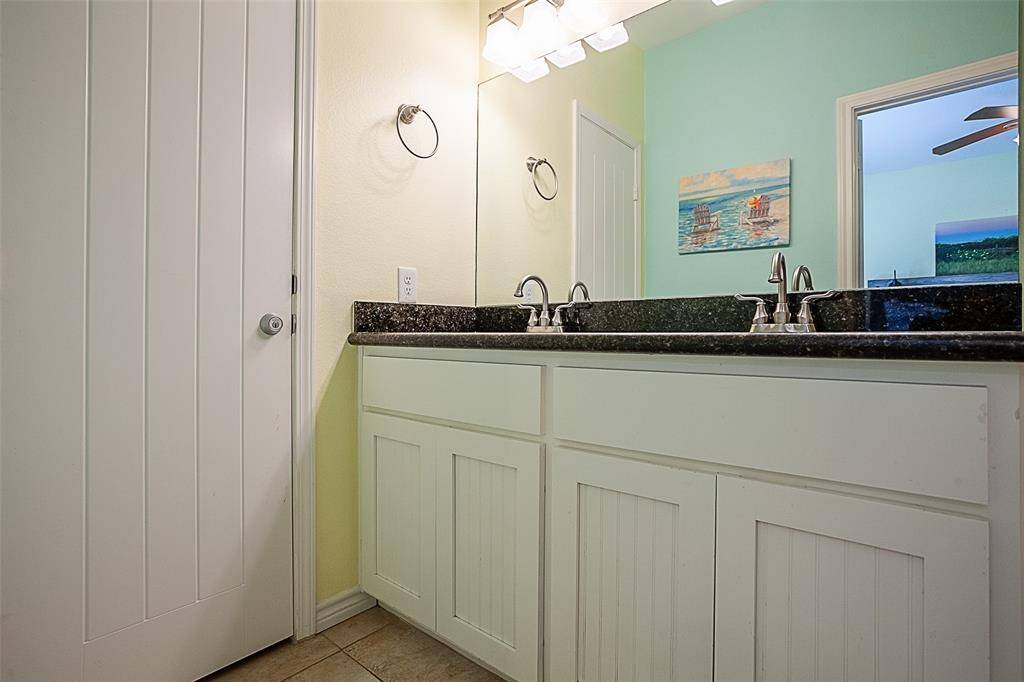 Primary ensuite bathroom with dual sinks, large mirror and storage closet.