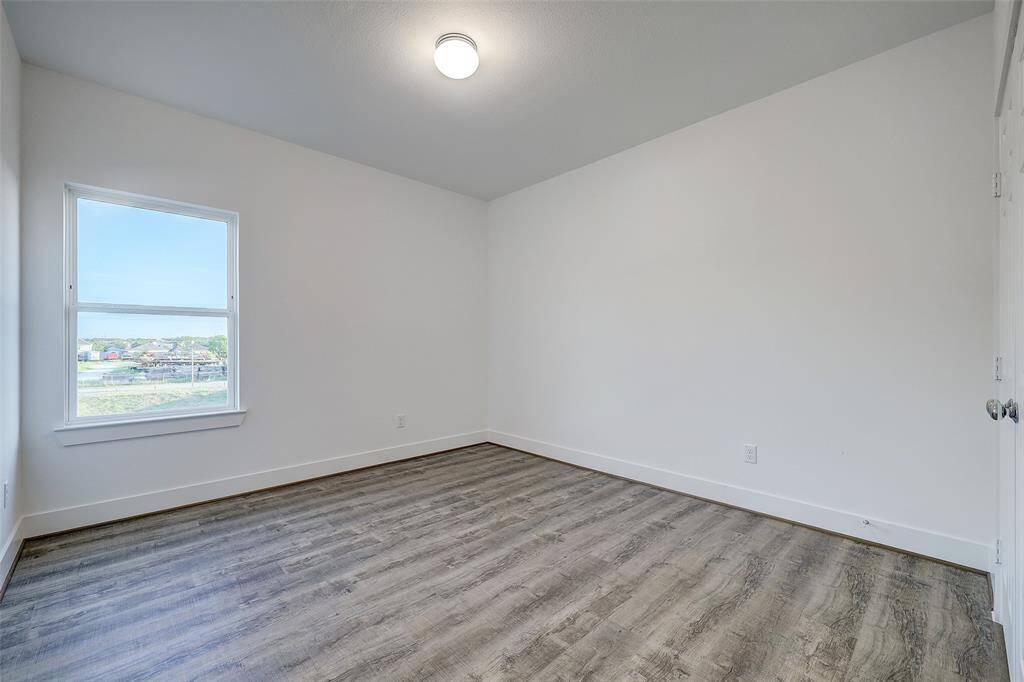The secondary bedroom offers 10ft ceilings, a large window overlooking the back of the home, and durable LVP flooring throughout the room.