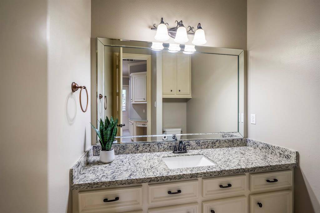 A lighted vanity area offer a large mirror, lots of cabinetry and neutral toned paint colors.