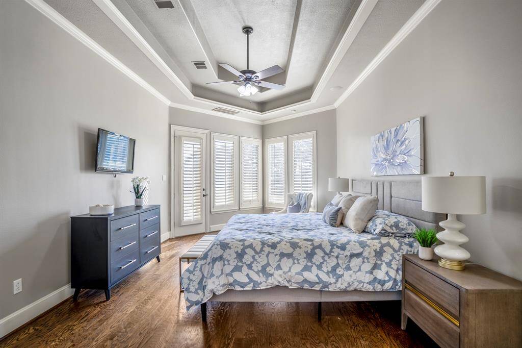 The primary suite features beautiful double trey ceilings, hand scraped wood floors, a wall of windows and door leading out onto the private patio.