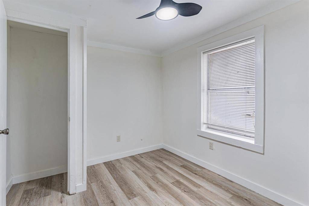 Bright primary bedroom featuring sleek flooring and ample natural light from a large window.