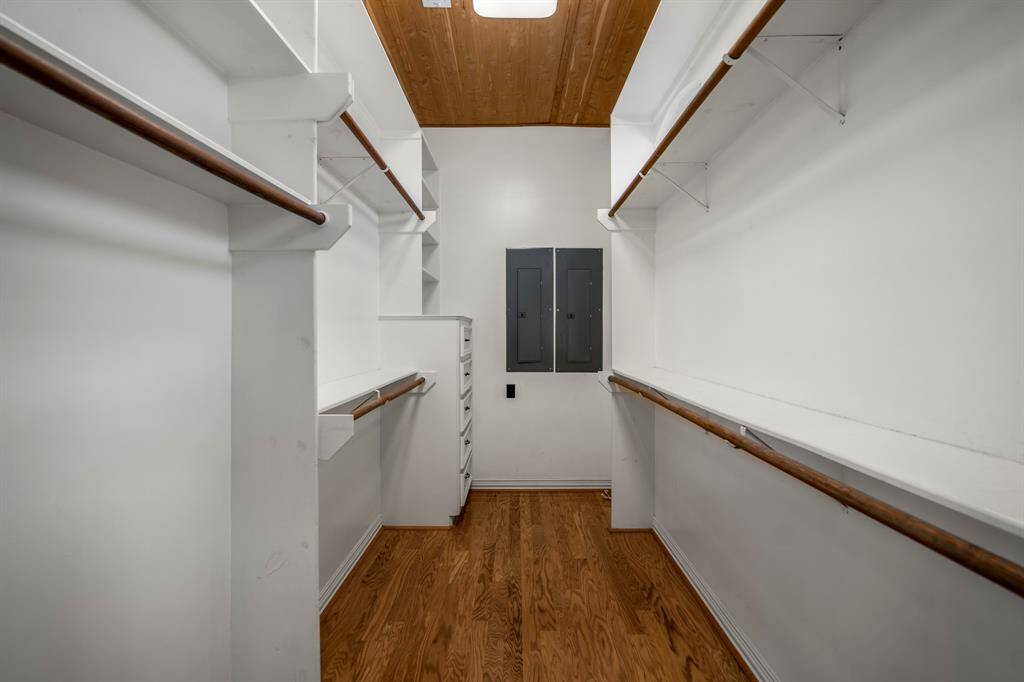 The primary bedroom suite offers dual closets, and this is one of the two closets with hardwood floors and plenty of hanging space as well as a drawers for folded items.