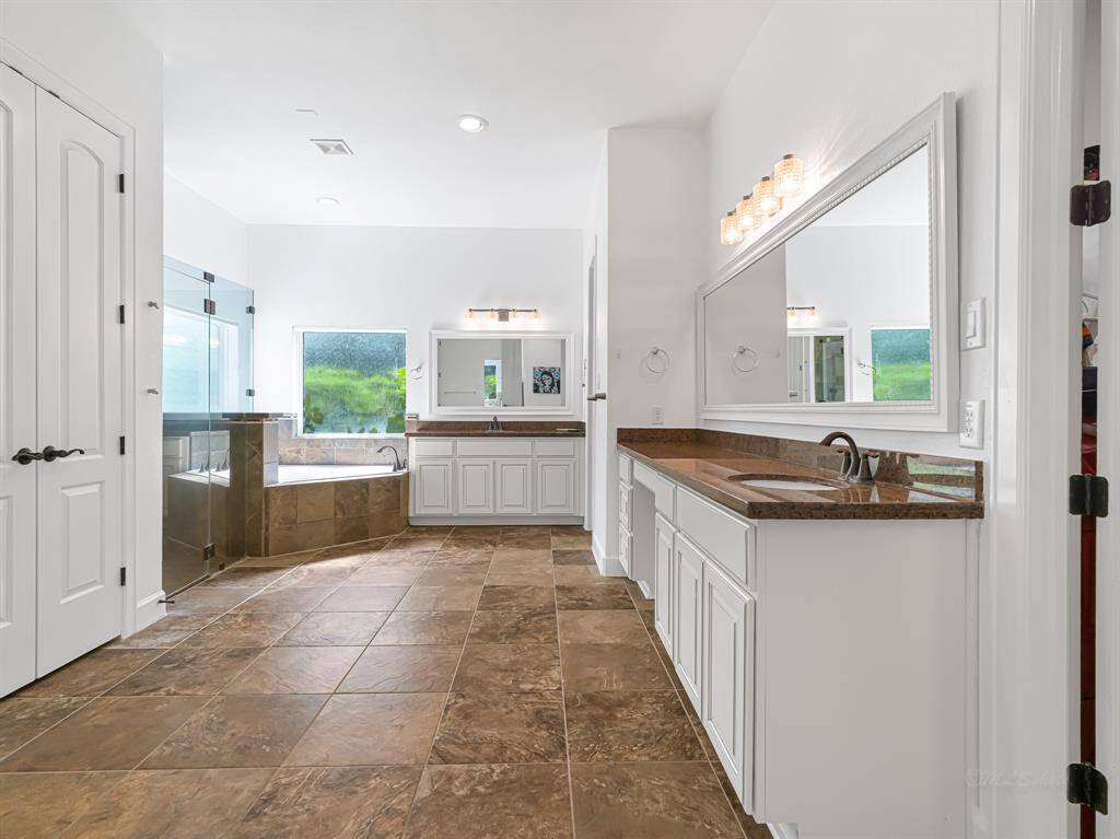 En suite bathroom has gorgeous natural light, double vanities, a walk-in shower, jacuzzi tub and large linen closet