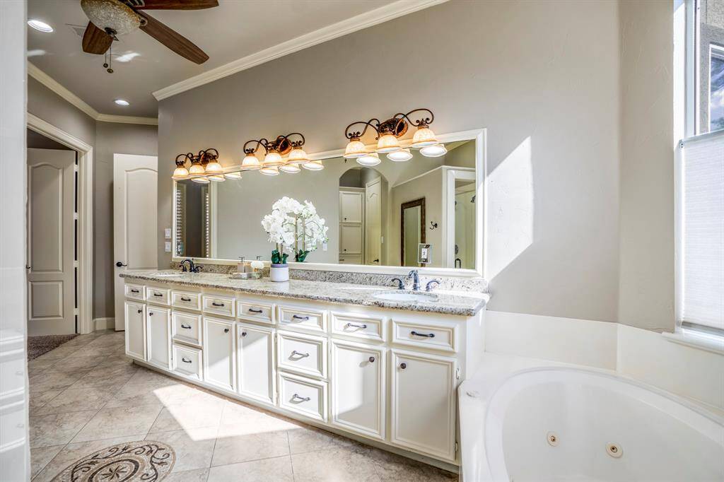 Another view of the expansive primary bathroom, large vanity, dual sinks, whirlpool tub and beautiful inlaid tile.