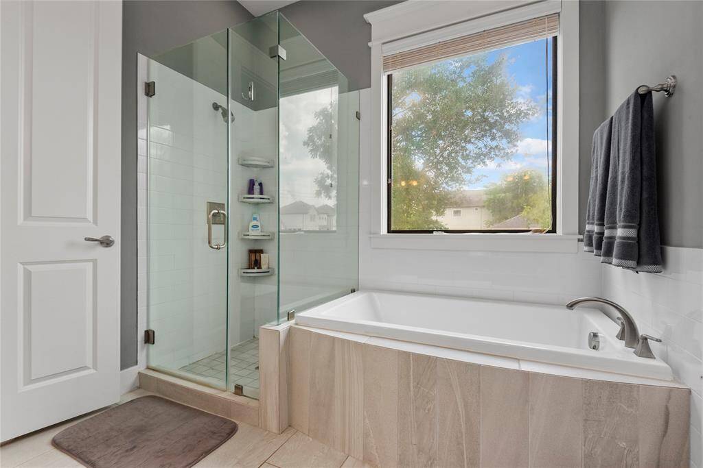 An elegant primary bath with modern fixtures, a soaking tub, and a separate walk-in shower.