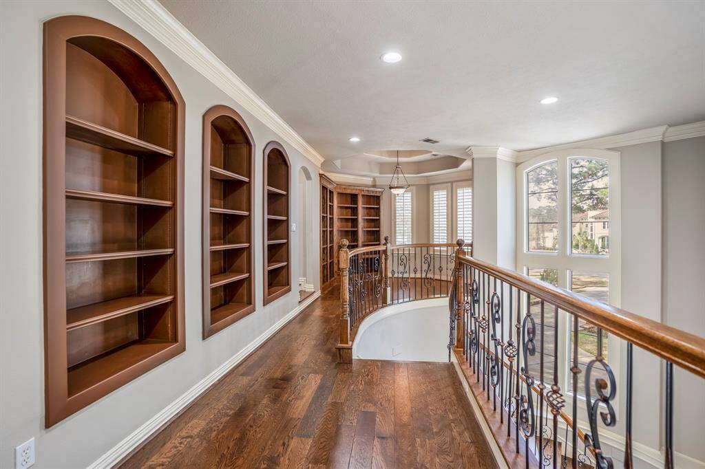 The upstairs gameroom area and catwalk offer custom arched bookshelves, beautiful oak wood floors, scroll iron railings and recessed lighting.
