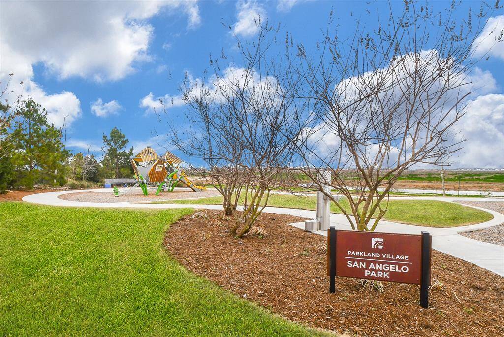 This photo showcases a well-maintained park in Parkland Village, featuring a modern playground and open green spaces, ideal for families and outdoor activities.