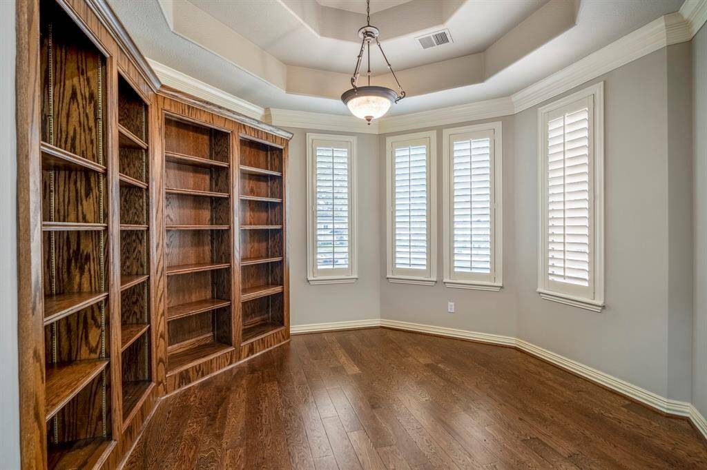 You have a beautiful library in the corner with four custom  wood shelving units. as well as large windows that allow for natural light that can be defused with the plantation shutters, a great seating area.