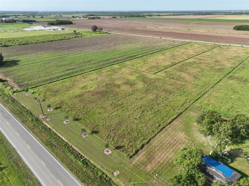 This is a spacious, open rural lot with clear skies and a few scattered trees, offering plenty of space for a custom home build with room for expansive landscaping or farming.
