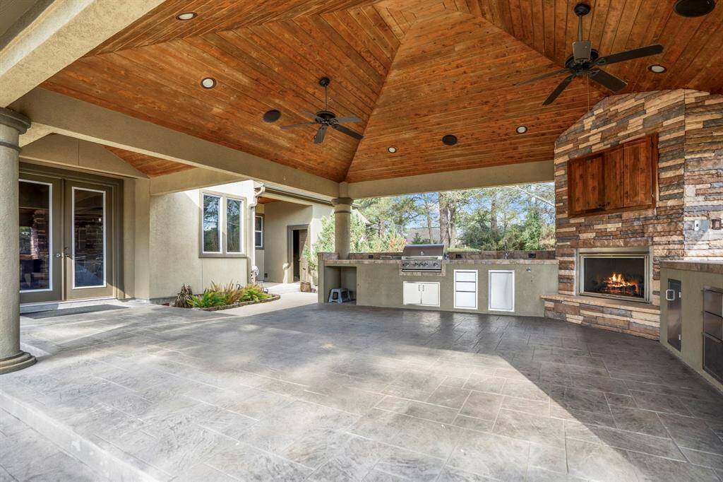 A huge cabana offers an outdoor grill with side-burner, gas fireplace, TV with custom wood doors, cedar beaded ceiling with recessed lighting and stunning views of the golf course.