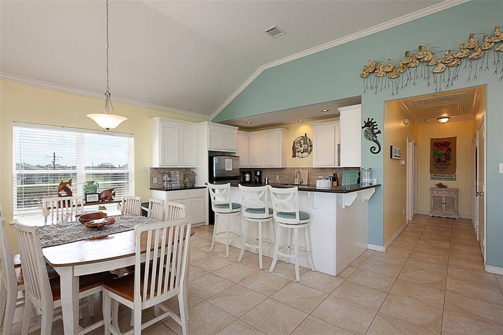 Lovely kitchen with granite countertops, stainless steel appliances, a large table and dining area, breakfast bar, and crown moulding.