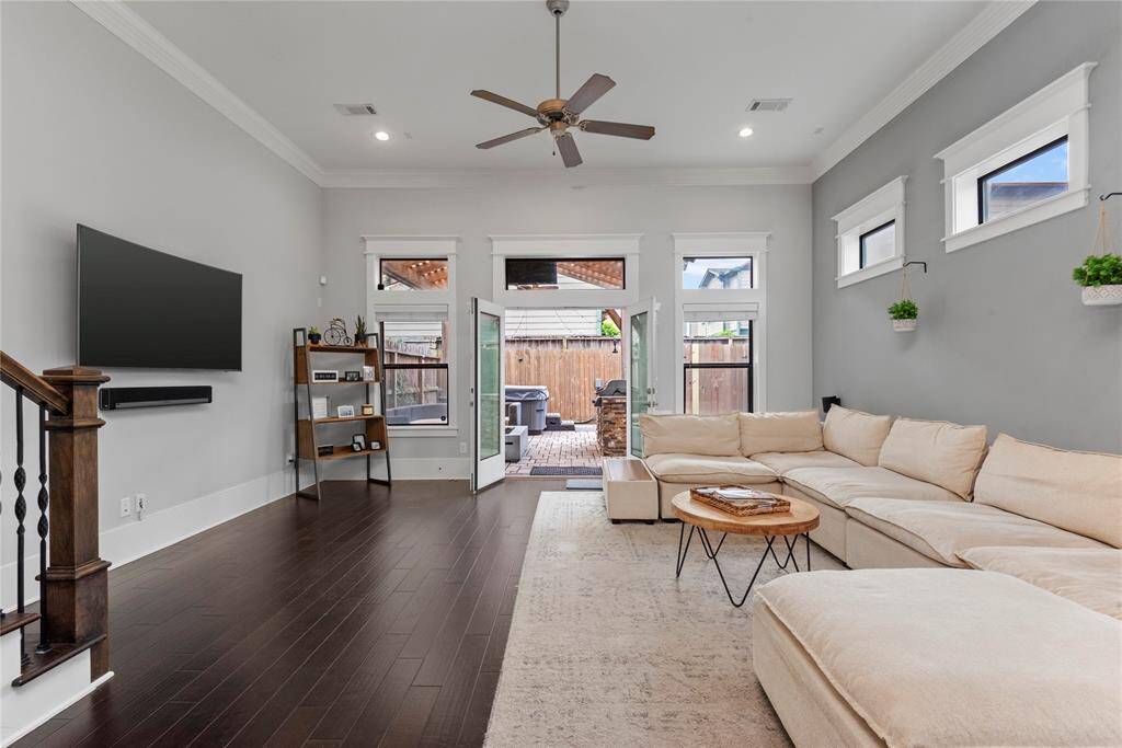 An inviting open living area with beautiful wood floors, crown molding, and ceiling fans, creating a warm and welcoming ambiance.
