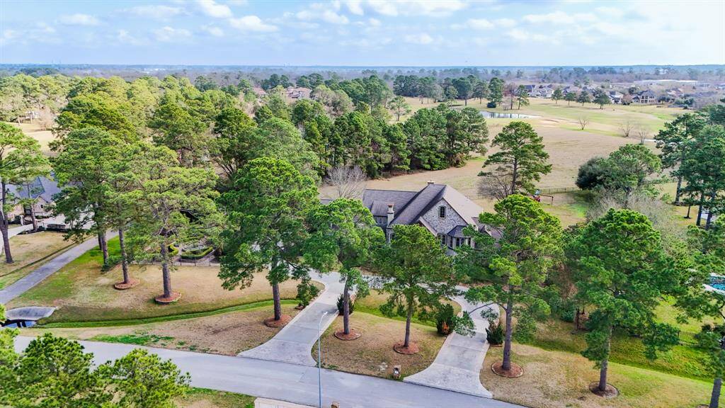 An aerial view of the home with the golf course in the background, this home offers all-weather enjoyment.