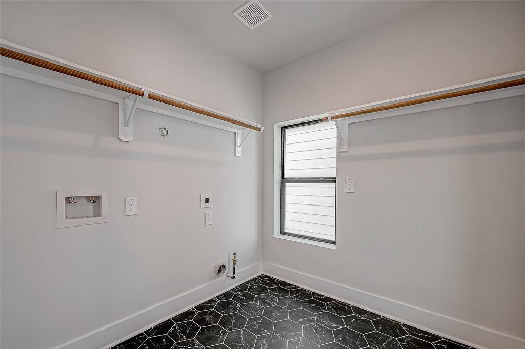 This photo showcases a the third floor. The landing is bright, modern with light wood flooring and a staircase featuring wooden handrails and black spindles. The space is well-lit with recessed lighting and has a window providing natural light. The primary bedroom and a third bedroom is on this floor.