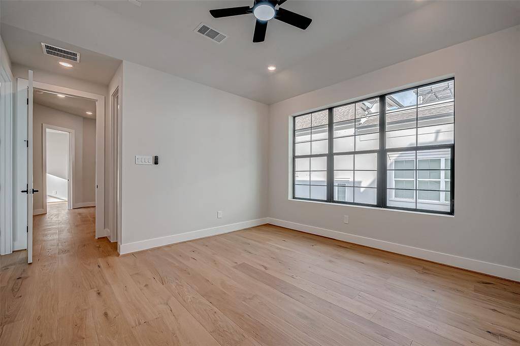 Spacious walk-in closet with ample shelving and hanging space, featuring light wood flooring and a modern, clean design.