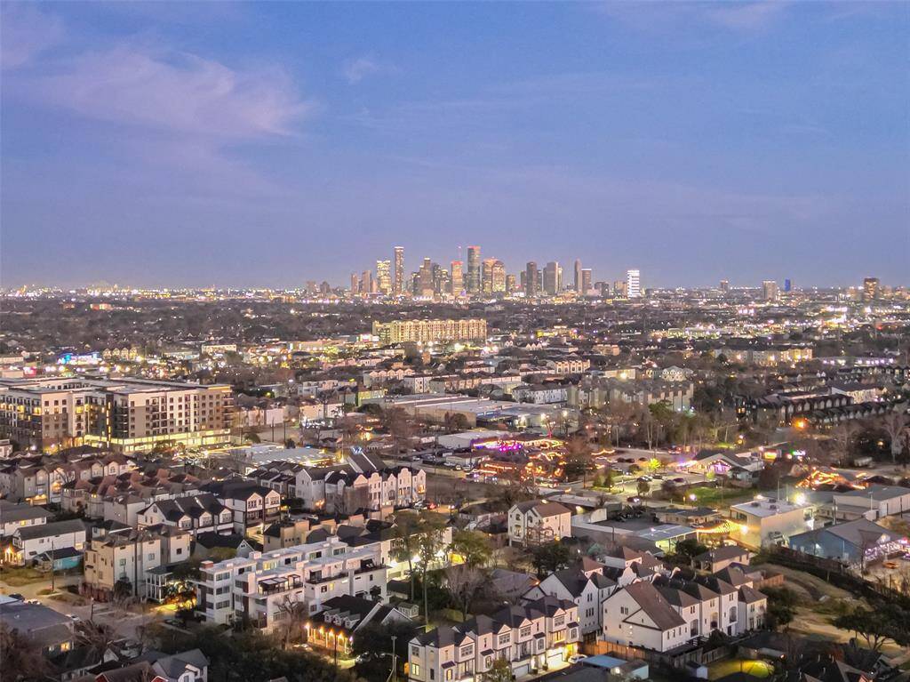 This photo showcases a vibrant cityscape at dusk, featuring a sprawling urban area with well-lit buildings and a distant skyline. Ideal for those seeking a lively urban environment with proximity to city amenities.