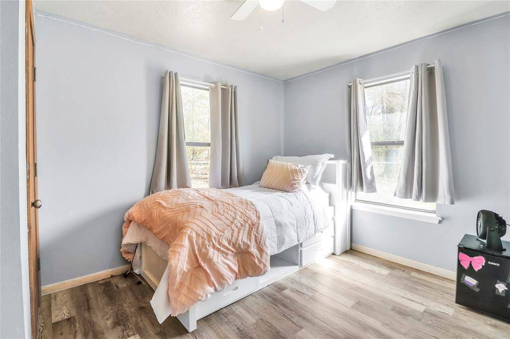 Cozy bedroom with abundant natural light and stylish laminate flooring. Perfect for guests or a home office.