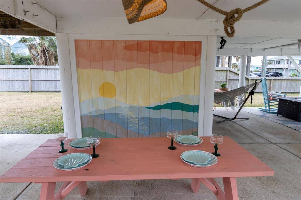 This photo shows a picnic table and a hand painted mural for an extra coastal decorative touch.  Come relax in the rocking chairs or the hammock.