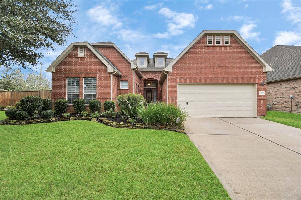 Charming brick home with lush landscaping, a spacious driveway, and a two-car garage. Enjoy inviting dormer windows and a cozy front porch.