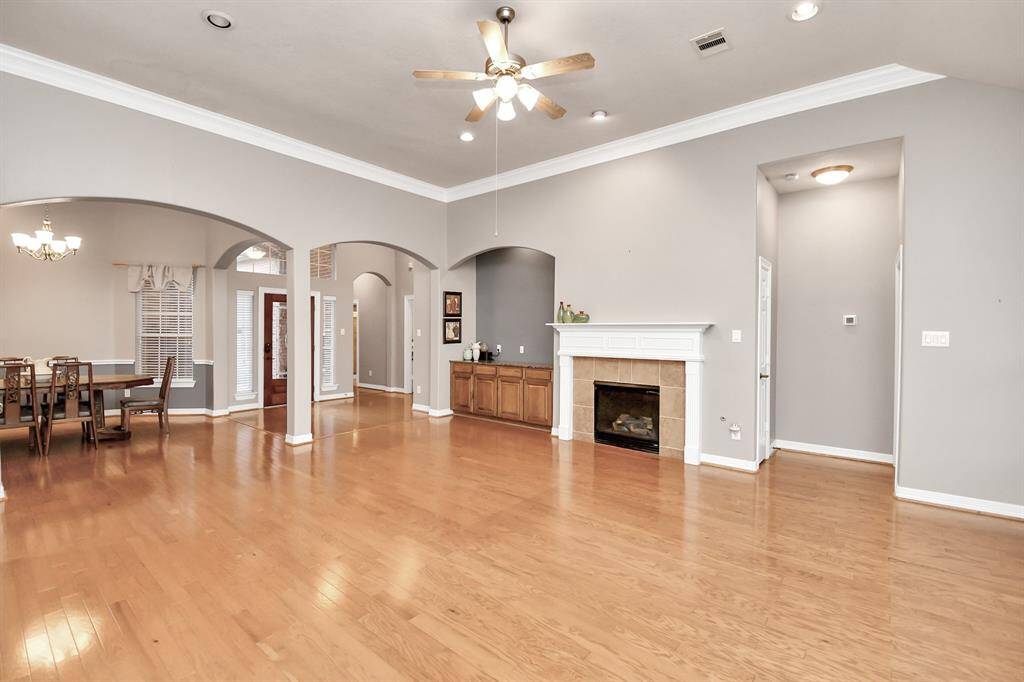 Discover a spacious living area with hardwood floors, a cozy fireplace, and elegant archways. The open layout seamlessly connects to the dining area, perfect for entertaining. High ceilings and neutral tones enhance the bright, inviting atmosphere.