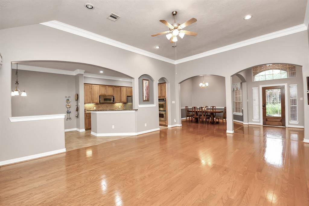 Experience the elegance of this open-concept living area with polished hardwood floors, 12-ft ceilings, and recessed lighting. The space seamlessly connects the living room, dining area, and modern kitchen with a breakfast bar. Enjoy abundant natural light from large windows and a stylish glass front door.