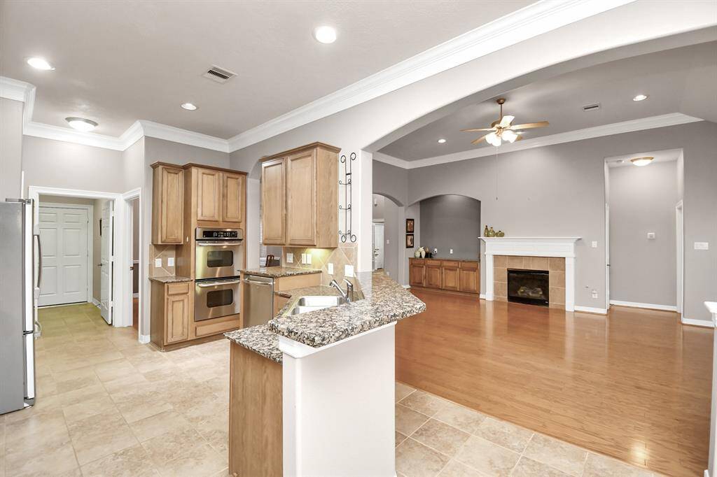 Open-concept design with elegant wood floors, seamlessly connecting the kitchen, dining area, living room, and breakfast nook. Features a cozy gas log fireplace and impressive 12-foot ceilings.