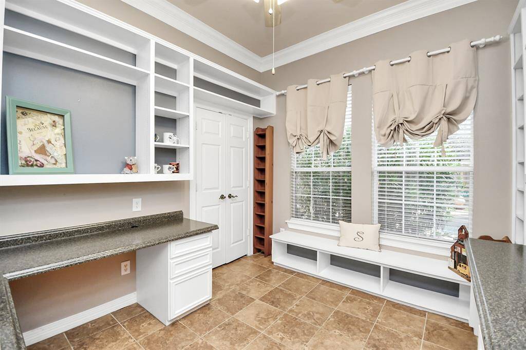 This bright room features built-in shelving and desks with a modern neutral palette. Large windows and tiled flooring make it perfect for a home office or study or a guest bedroom with the closet space!