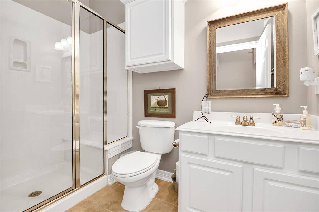 Elegant guest bathroom nestled between two bedrooms, featuring a spacious walk-in shower.