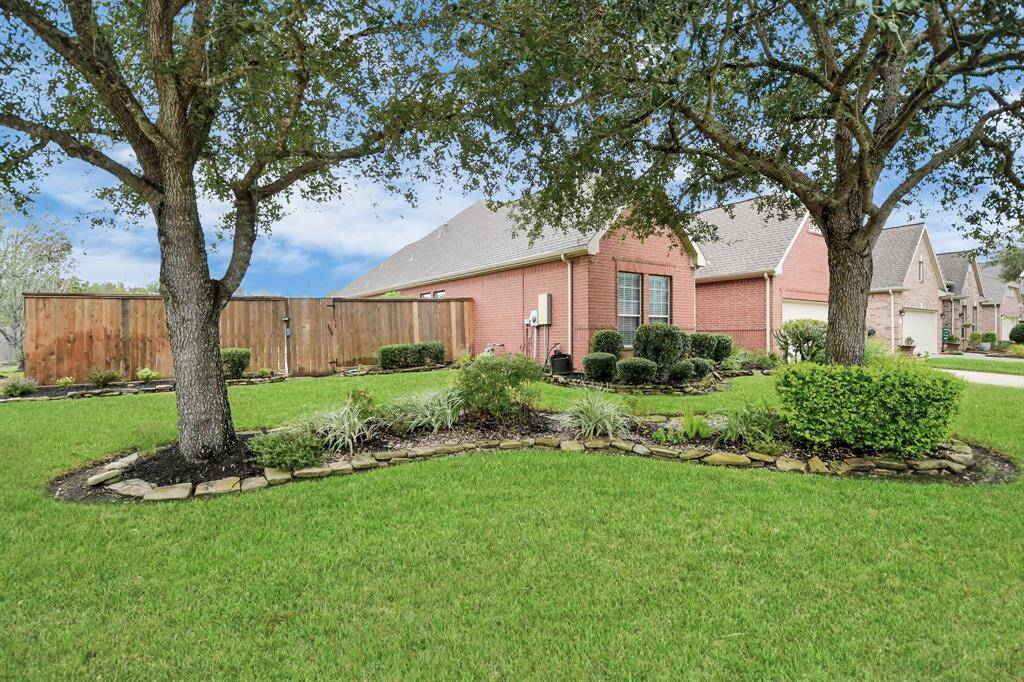 Charming brick home with a beautifully maintained front yard, mature trees, and a spacious driveway leading to a two-car garage. Classic curb appeal and ample parking.