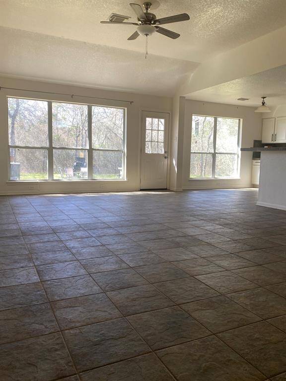 This spacious room features large windows offering abundant natural light, tile flooring, and a ceiling fan, providing a bright and airy atmosphere perfect for living or dining.