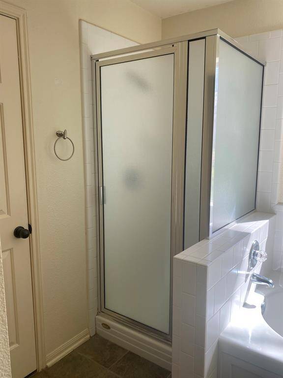 This bathroom features a modern glass-enclosed shower with frosted panels adjacent to a tiled bathtub, offering a clean and functional space.