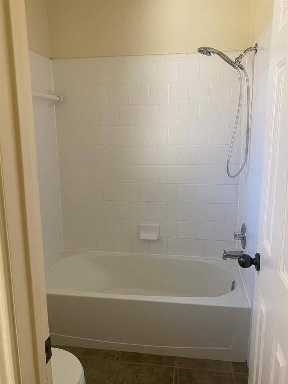 This bathroom features a clean, white tiled shower and tub combination with a handheld showerhead. It has a simple, functional design with neutral tones, providing a fresh and inviting space.