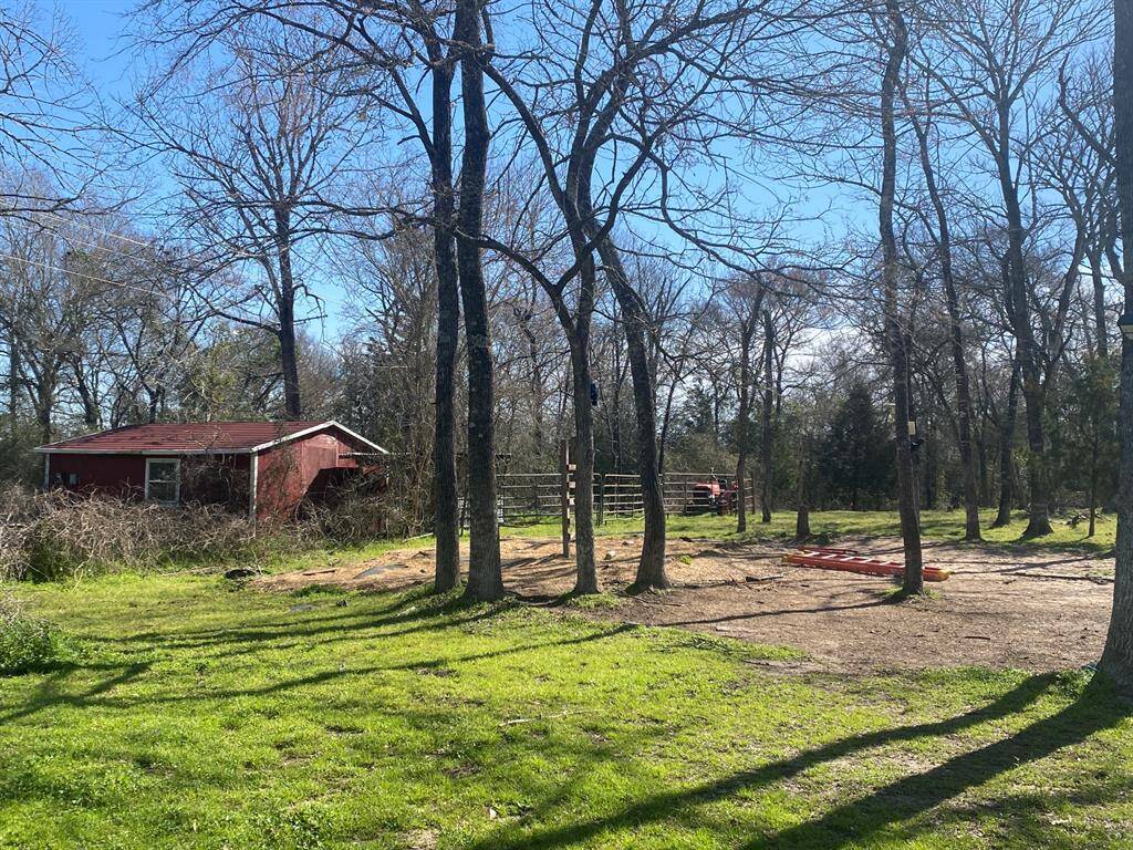 Charming property with a rustic red shed, surrounded by mature trees and open grassy areas. Ideal for those seeking a peaceful, natural setting.