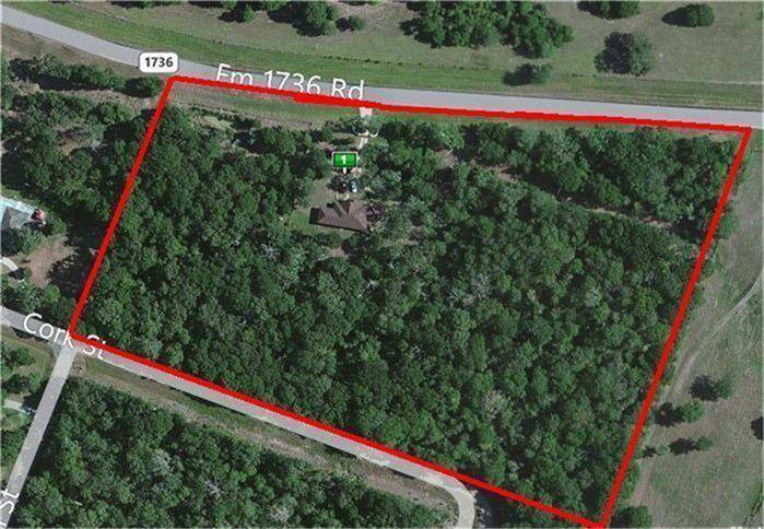 This aerial photo shows a heavily wooded property outlined in red, located near FM 1736 Rd. It includes a structure centrally positioned within the trees, offering privacy and natural surroundings. Ideal for buyers seeking seclusion with road access.