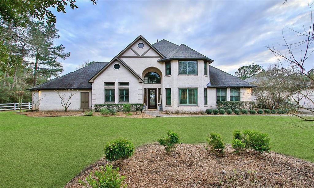 This elegant home features a modern brick exterior with a spacious, manicured lawn. It has a symmetric design with a prominent entrance and large, arched windows, situated in a serene setting.