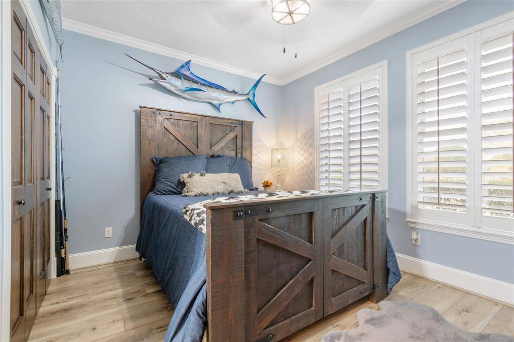 One of the secondary bedrooms that is located downstairs. The room is painted in a soothing blue tone, complemented by natural light from white plantation shutters. Perfect for a serene retreat.