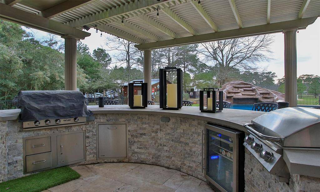 Outdoor kitchen with granite counters, beverage refrigerator, griddle, gas grill, & bar area for extra seating for your guests. Travertine patio, extensive pergola with decorative columns, and plenty of room for your guests makes this the perfect place to entertain!